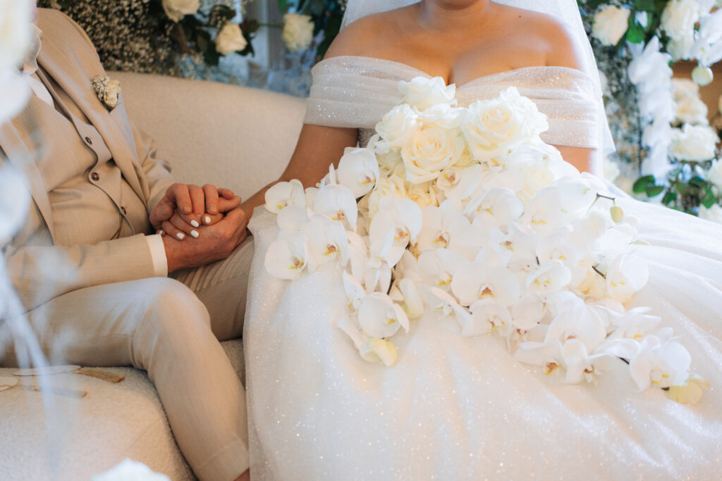 Liebevoll hält das Hochzeitspaar ihre Hände mit traumhaften Hochzeitsstrauß.