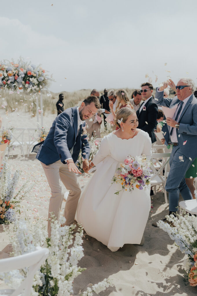 Hochzeitspaar mit Blütenwurf bei Zeremonie am Strand